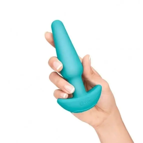 A hand holding a blue plastic toy from the b-Vibe 7-Piece Anal Training Kit and Education Set