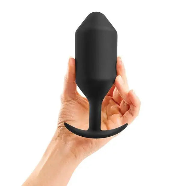 Hand holding b-Vibe Weighted Snug Plug 6 - 515 Grams black bottle