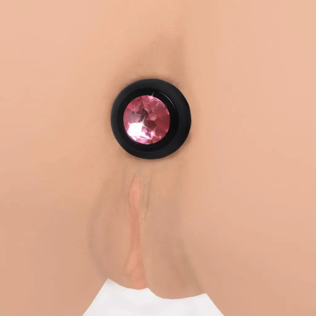 Pink gem anal plug: Vibrating silicone plug with pink gemstone in black frame