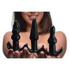 Set of three black silicone plugs from the 4 Piece Vibrating Anal Plug Set held in hands