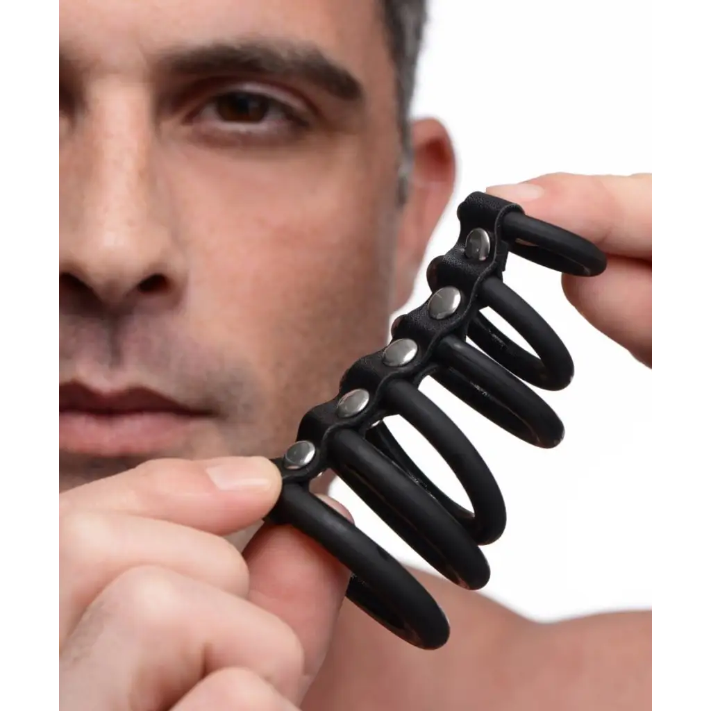 A man holding black earbuds next to a 6 Ring Silicone Chastity Device for male restraint