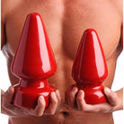 Two red Anal Destructor Plugs held against a person’s torso for ultimate pleasure