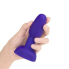 Hand holding the b-Vibe Petite Rimming Plug in purple color for enhanced pleasure