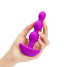 Purple b-Vibe Triplet Anal Beads in hand, showing size and flexibility