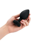 A hand holding a black plastic ball from the b-Vibe Vibrating Jewel Plug