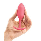 Hand holding b-Vibe Weighted Snug Plug 2 - 114 Grams in pink