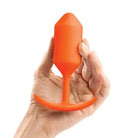 Hand holding orange b-Vibe Weighted Snug Plug 3 - perfect weighted snug plug for comfort