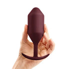 Hand holding wine bottle; discover b-Vibe Weighted Snug Plug 5 for enhanced pleasure