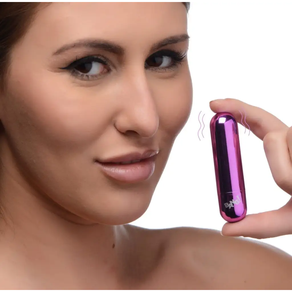 Woman holding BANG! 10x rechargeable vibrating metallic bullet near her face