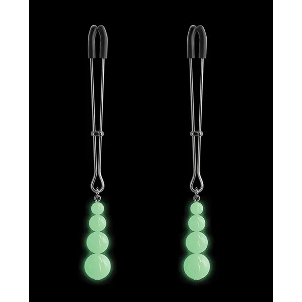 Green earrings with dangling stones resembling bound nipple clamps on a black background