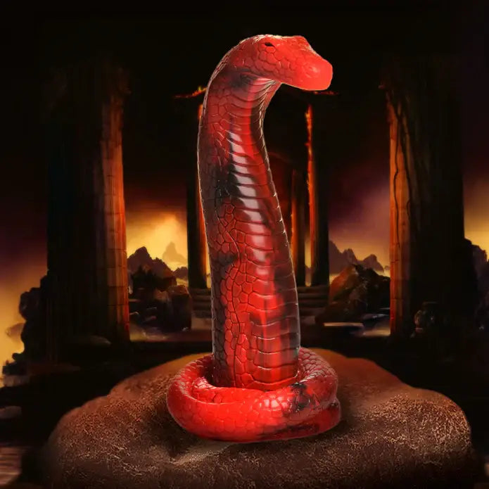 A red snake on a rock in front of a fireplace with the Creature Cocks King Cobra Silicone Dildo