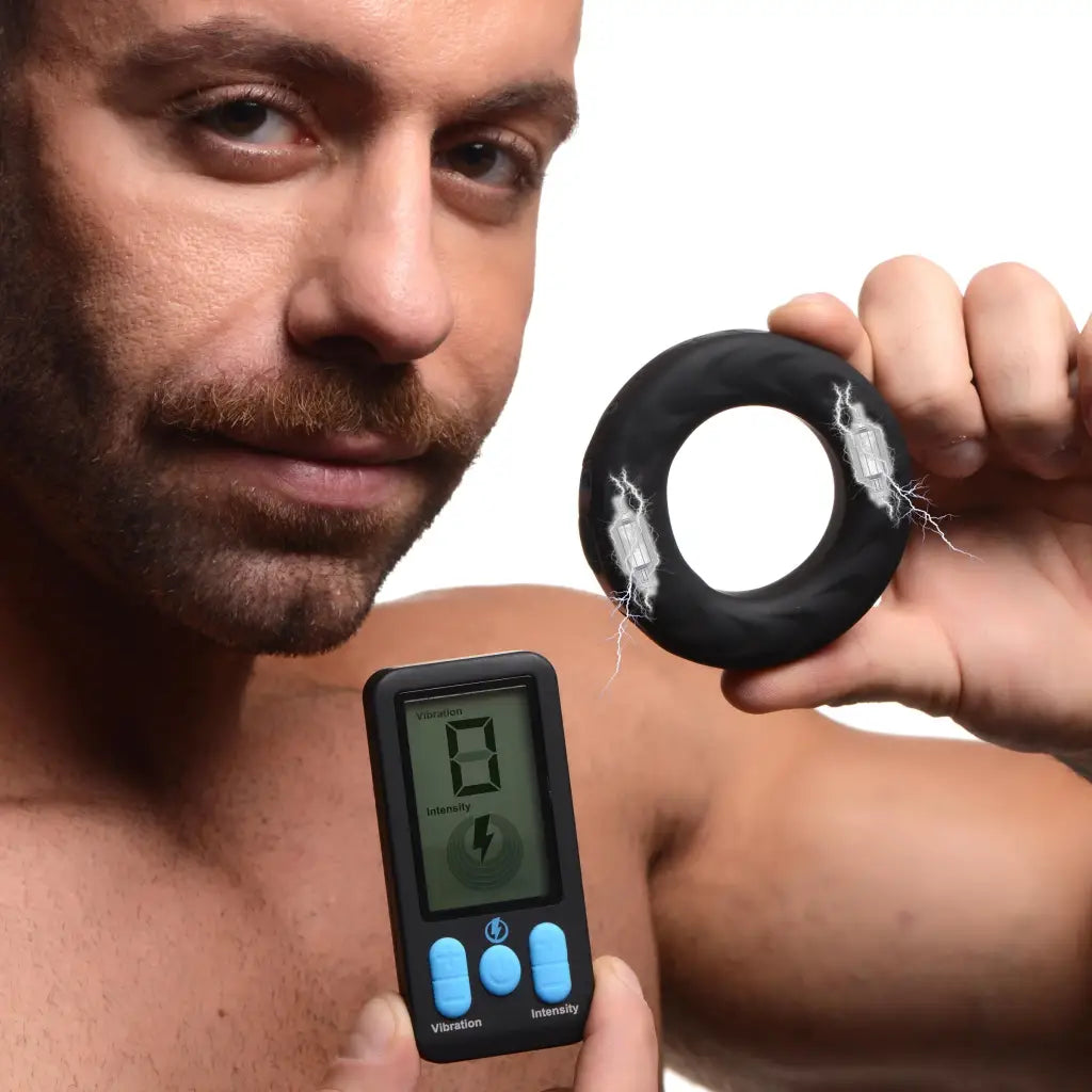 A man holding a black and white digital device for E-stim Pro Silicone Vibrating Cock Ring