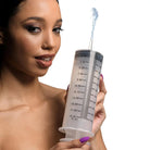 Woman holding oversized enema syringe with measurement markings and silicone tube