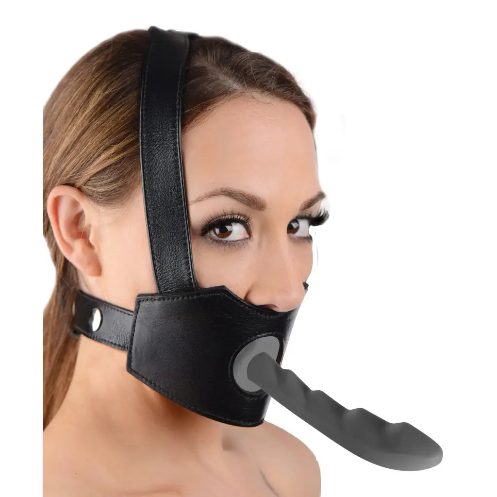 A woman wearing a black leather mask features the Face Fuk II Dildo Face Harness