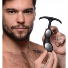 Tattooed hand holding a premium silicone weighted prostate plug in black and white