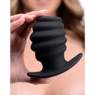 A woman holding Hive Ass Tunnel Silicone Ribbed Hollow Anal Plug in black