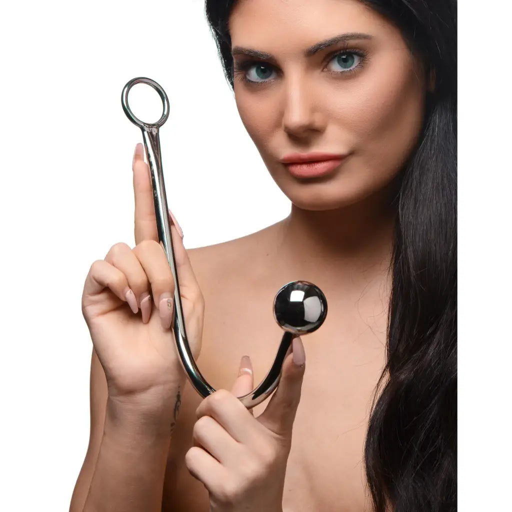 A woman holding a pair of scissors beside a Hooked Stainless Steel Anal Hook