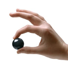 Person holding black ben wa balls between thumb and forefinger from Jaded Glass Ben collection