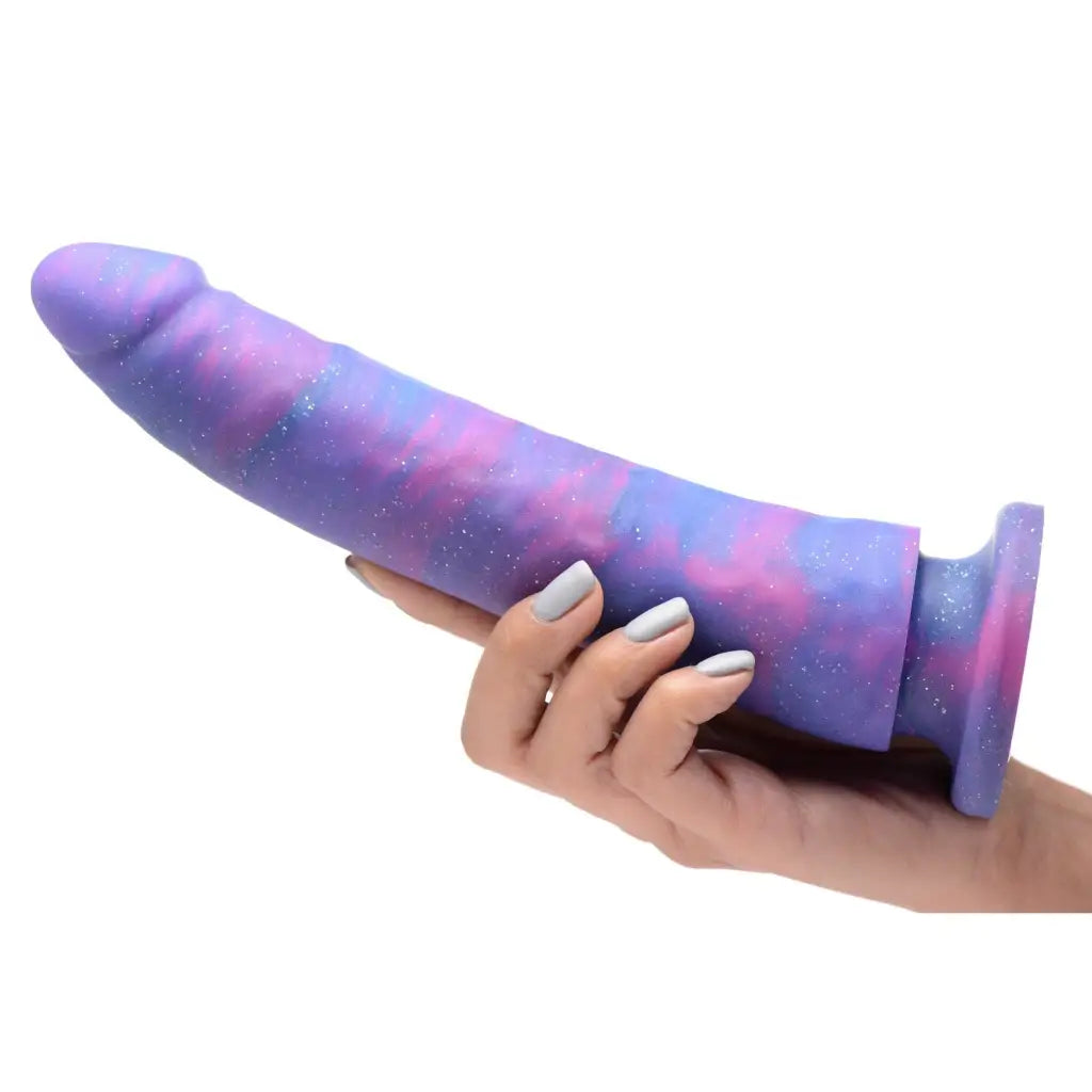 A hand holding a galaxy pillow displayed next to the Magic Stick Glitter Silicone Dildo