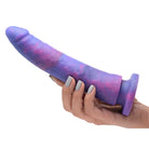 A hand holding a Magic Stick Glitter Silicone Dildo with a purple and blue galaxy design