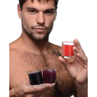 Shirtless man holding Master Series Flame Drippers Candle Set with colorful liquids