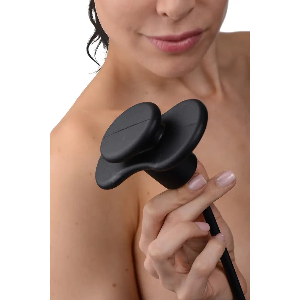 A woman holding a black hairbrush with the Master Series Inflatable Silicone Butterfly Gag