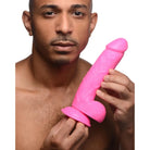 Pink Pop Peckers 8.25’ Dildo with Balls and suction cup base held by a person’s hand