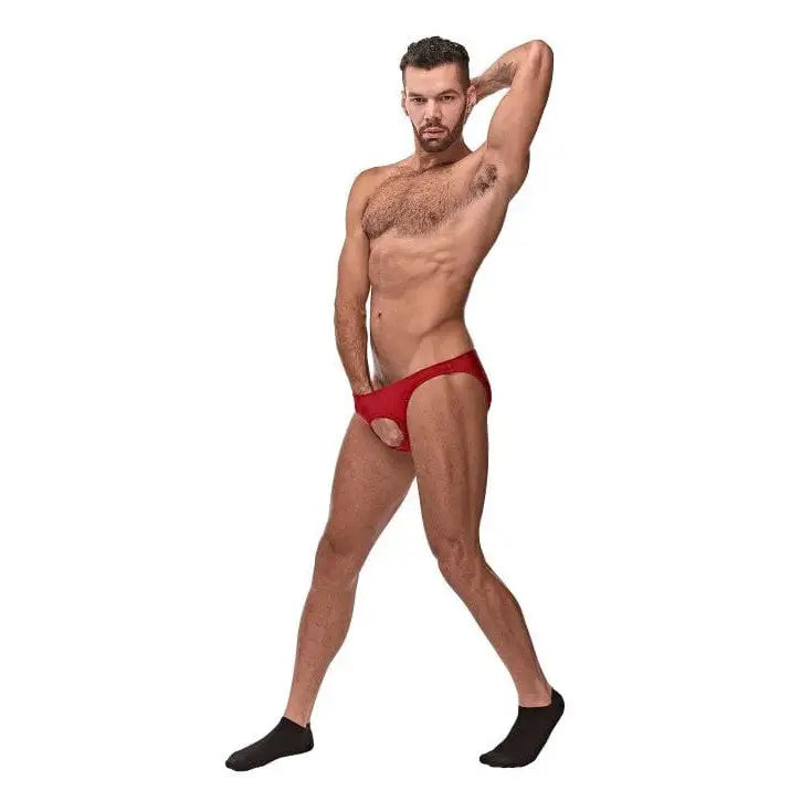 Muscular shirtless man in red nylon spandex pouchless briefs and black socks