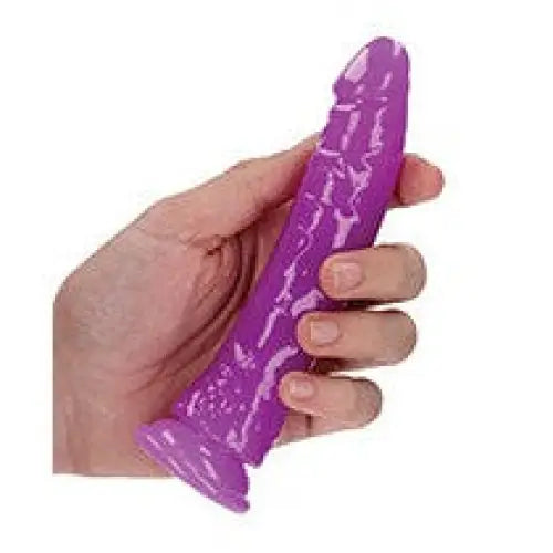 Purple silicone sex toy with textured surface held in a hand - RealRock Glow Dildo Neon Blue