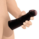 Black silicone extra large penis extender sleeve held in a hand