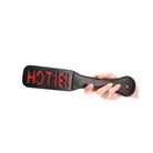 Shots Ouch Bitch Paddle Black with ’HOT’ in red, held by hand, perfect for kinky play