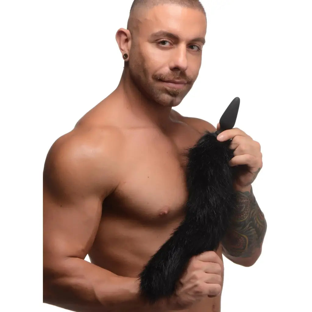 Muscular shirtless man holding duster with Small Anal Plug and interchangeable Fox Tail