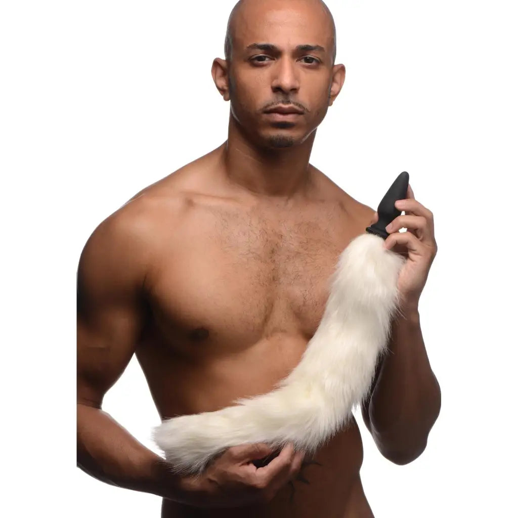 Shirtless man holding small anal plug with white fox tail, perfect for playful adventures