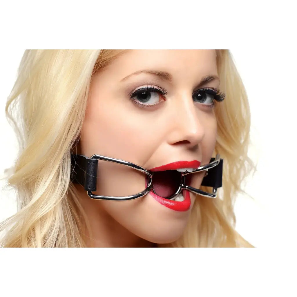 Blonde-haired person with red lipstick wearing a Spider Open Mouth Gag or dental retractor