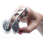 Hand with red nails holding Spikes Double Finger Pinwheel, a spiked metal roller tool