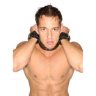 Shirtless muscular man with neck restraint and strict leather wrist cuffs from Strict Leather