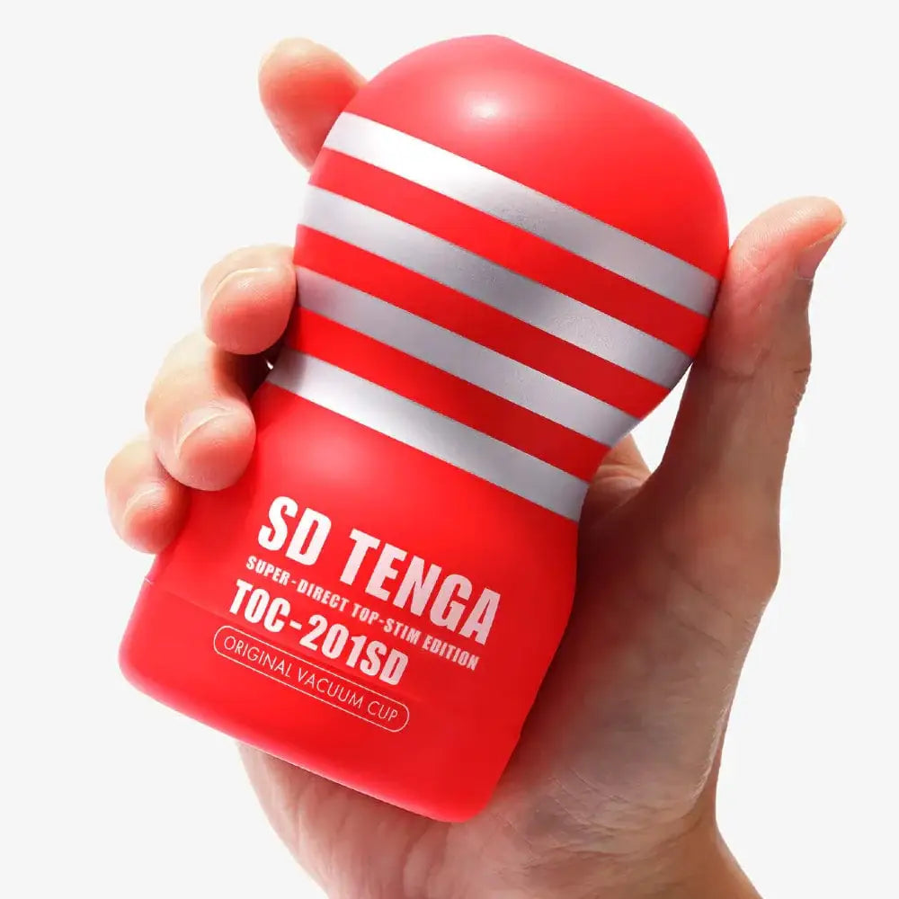 Hand holding Tenga SD Original Vacuum Cup, a red and white striped cylindrical object