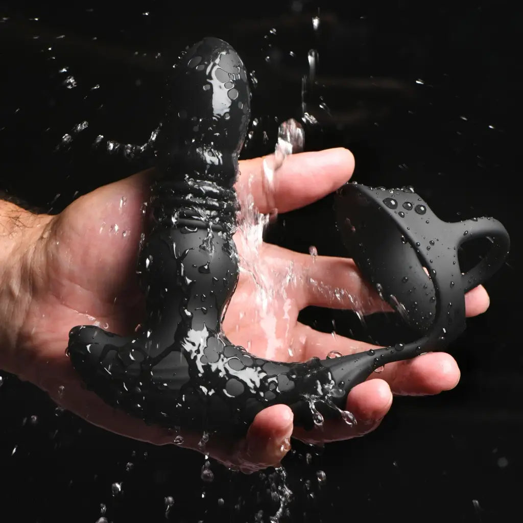 Black silicone thrusting vibrator with cock and ball ring being splashed with water