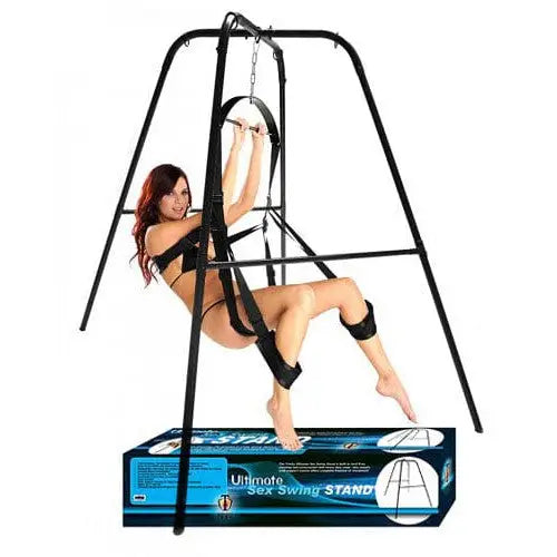 A woman in a harness hangs on the Trinity Vibes Ultimate Sex Swing Stand, enjoying the ride
