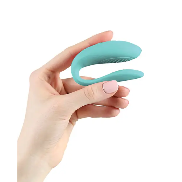 A hand holding the blue and green We-Vibe Sync Lite with single button intensity levels