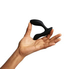 Hand holding We-Vibe Vector+ prostate and perineum stimulator, a black curved silicone toy