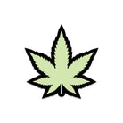 Stylized green pot leaf pin from Wood Rocket glows in the dark with black outline